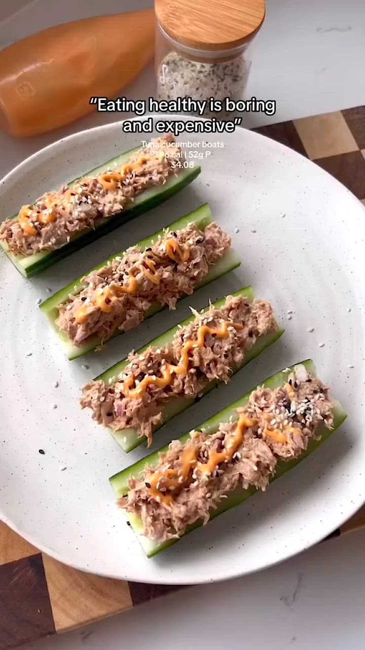 This may contain: four celery sticks with tuna and cheese on them sitting on a white plate