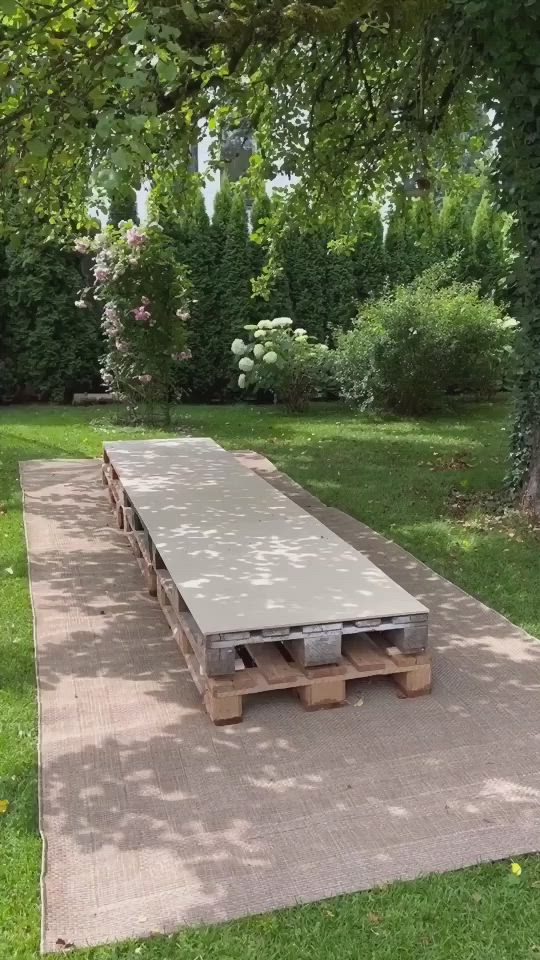 This may contain: a woman is throwing a frisbee in the air near a table made out of pallets