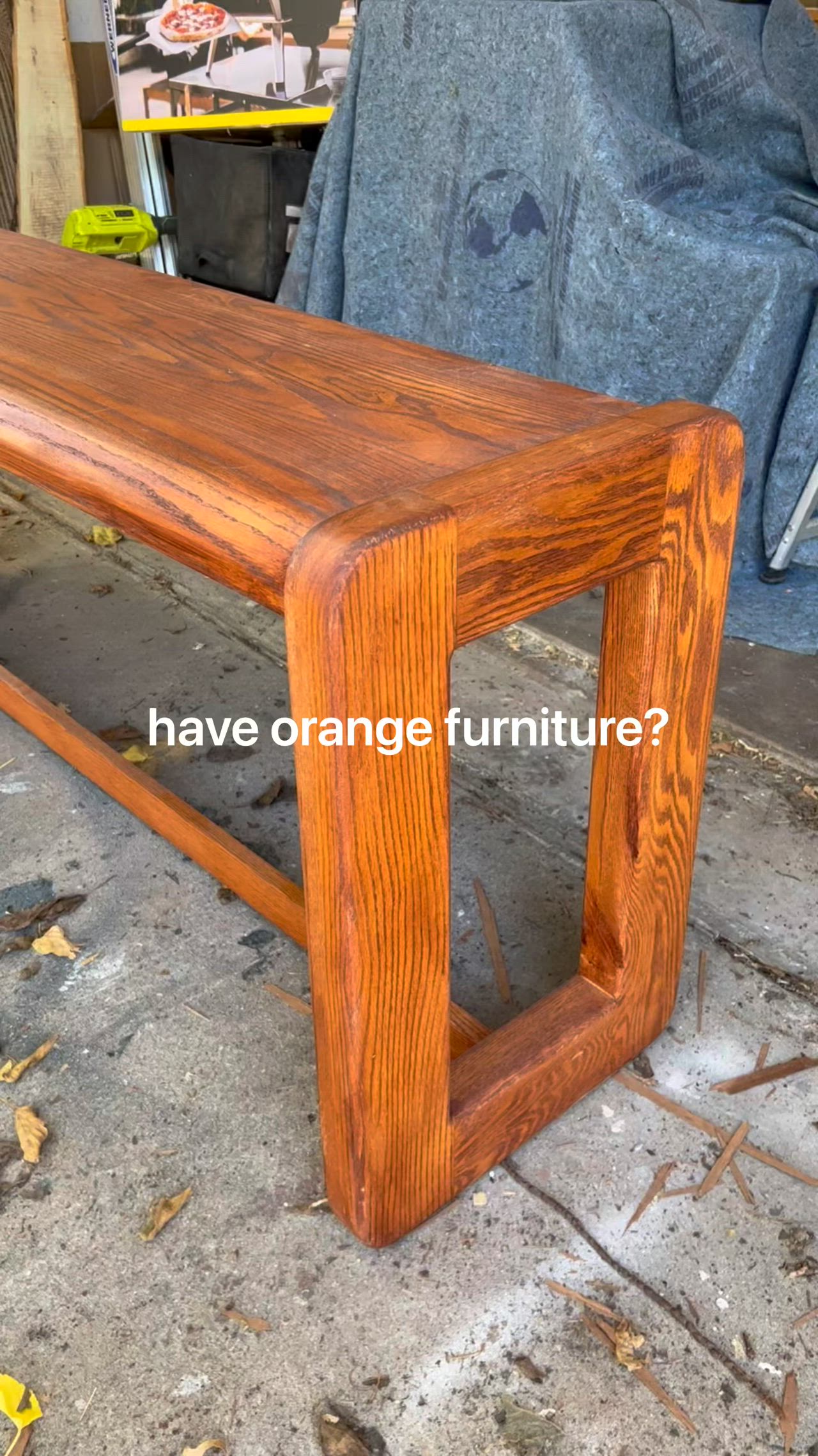 This may contain: a wooden bench sitting on top of a cement floor next to a blue chair with the words, have orange furniture? don't throw it out