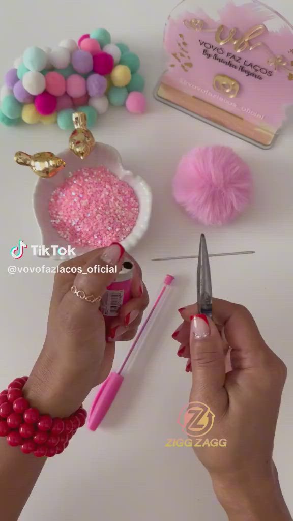 This may contain: a woman is cutting into some pink and white decorations on a table with other items