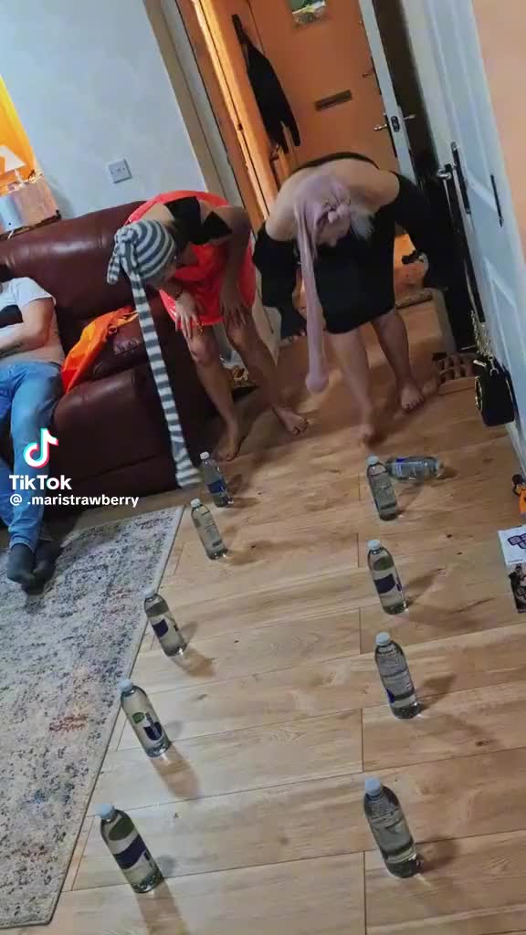 This may contain: several people are playing with wine bottles on the floor in front of a living room