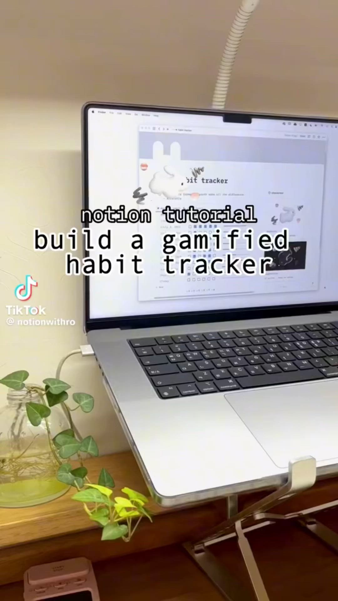 This may contain: a laptop computer sitting on top of a wooden desk next to a potted plant