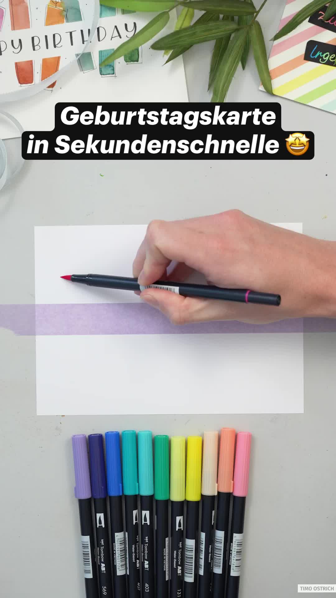 This may contain: a person holding a pen in front of a card with candles on it and the words geburtstagskarte in german