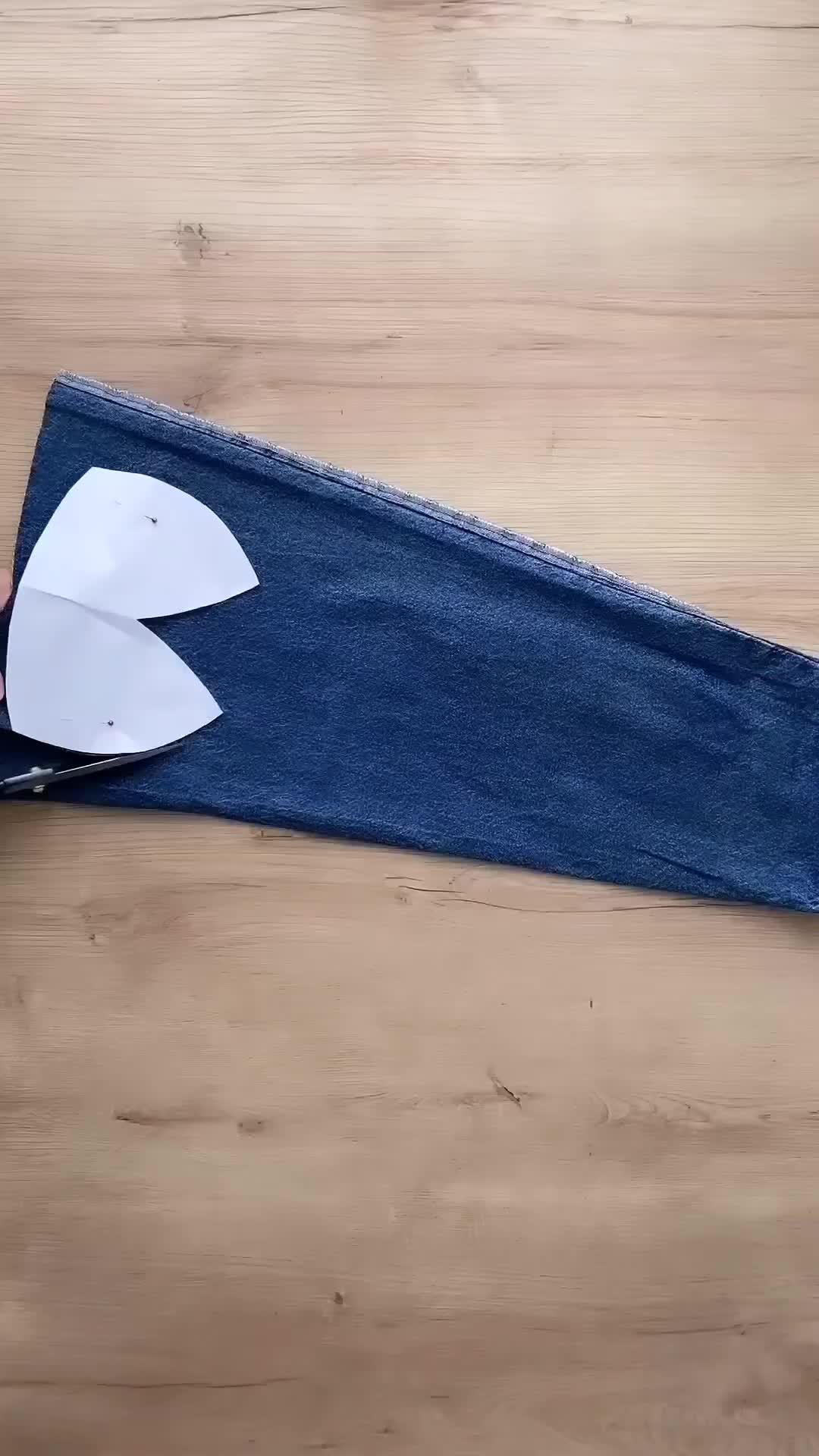 This may contain: a pair of scissors cutting out the back of a pair of jeans with paper on it