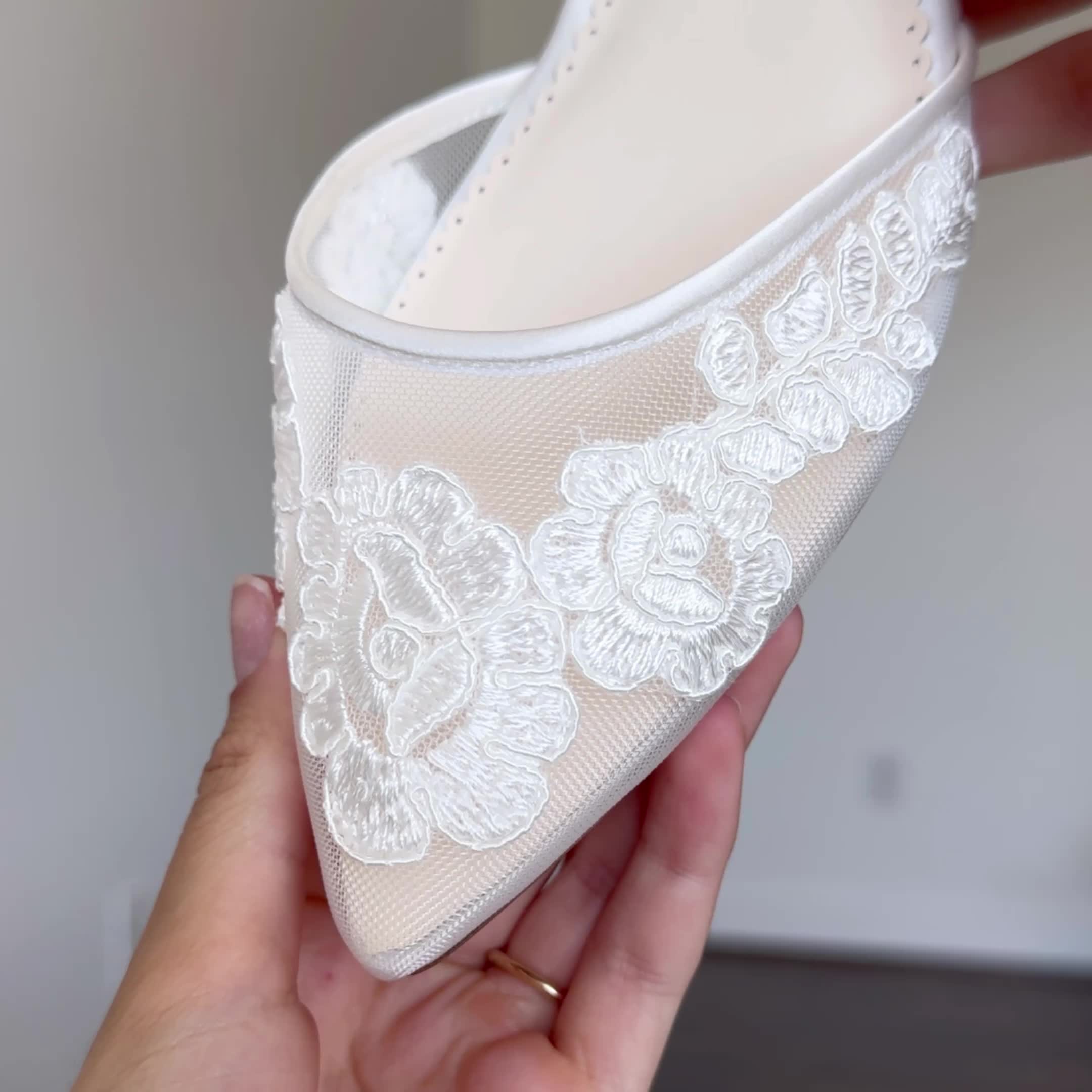 This may contain: someone is holding up a white shoe with flowers on the bottom and lace around it