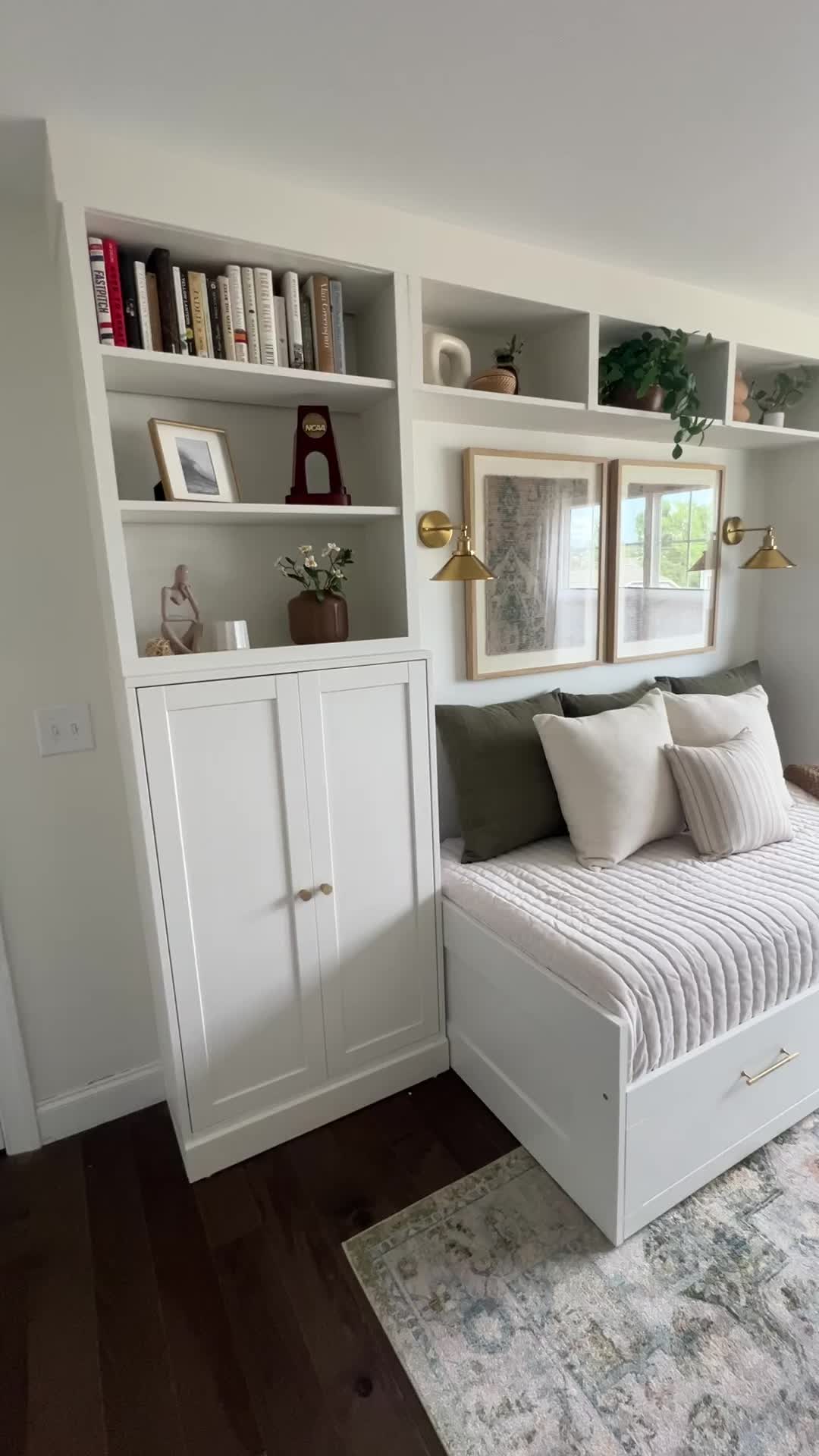 This may contain: a white day bed sitting in a bedroom next to a book shelf