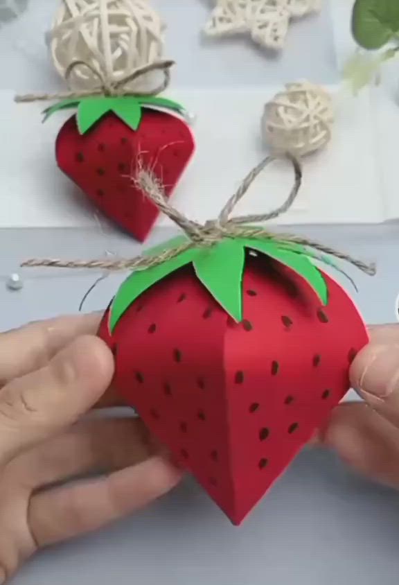 This may contain: someone is making a paper strawberry decoration