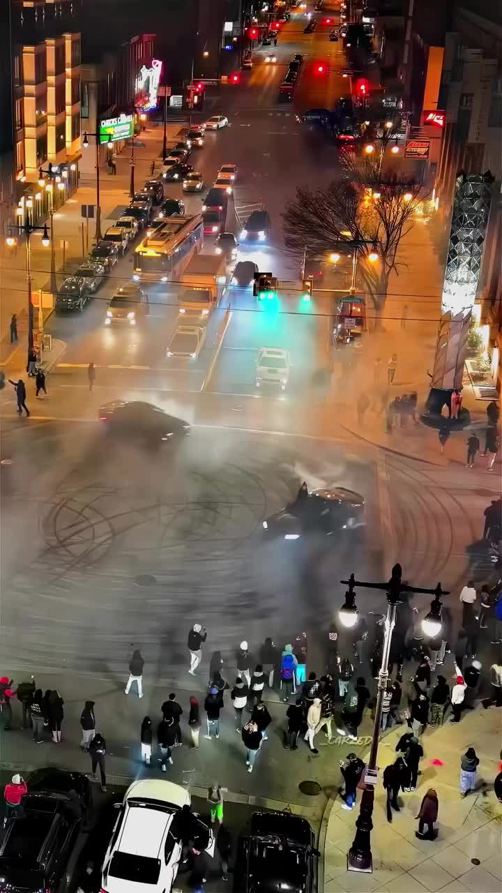 This may contain: an aerial view of a city street at night with cars and people on the sidewalk