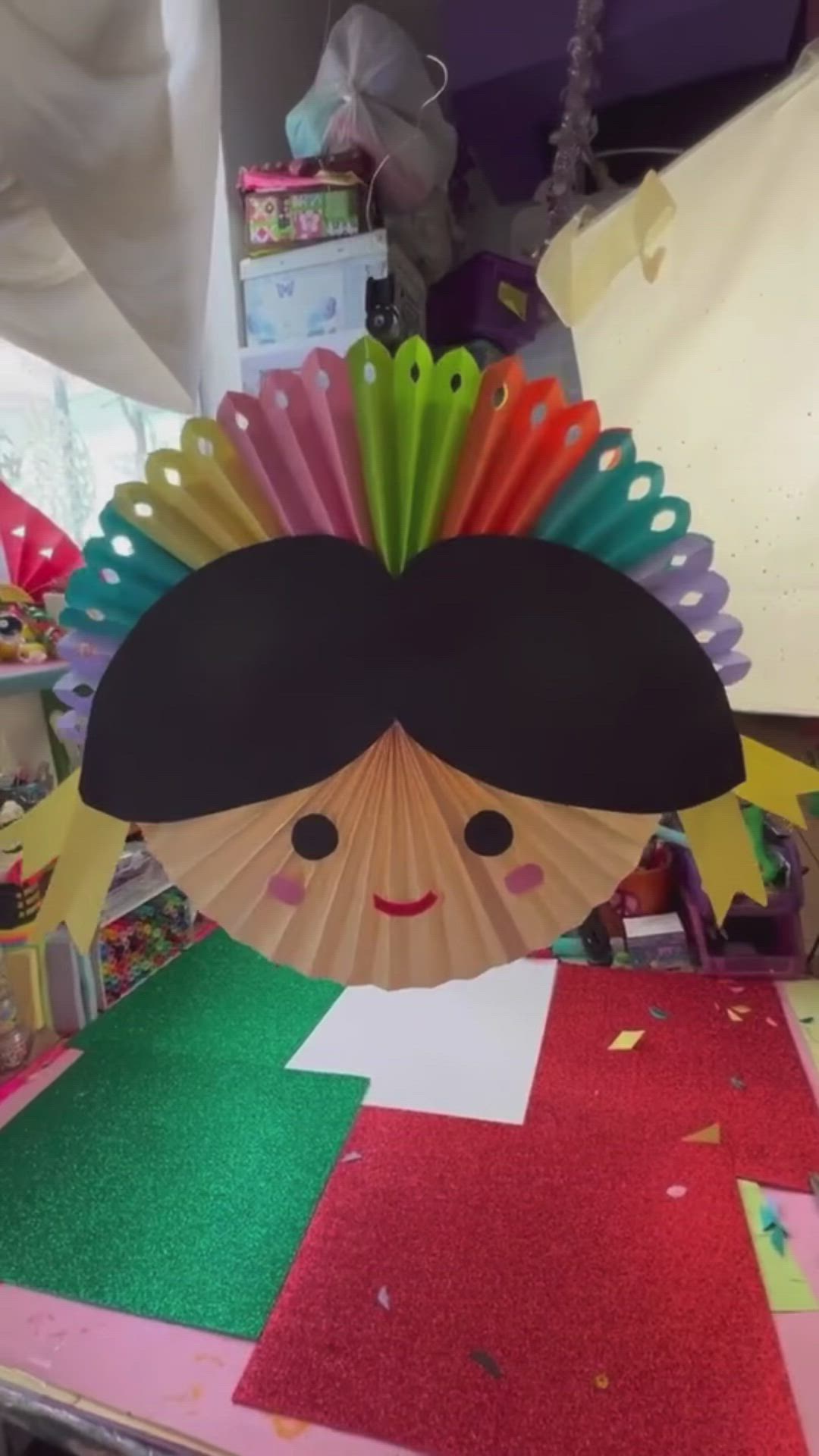 This may contain: a paper fan with a woman's face on it sitting on top of a table