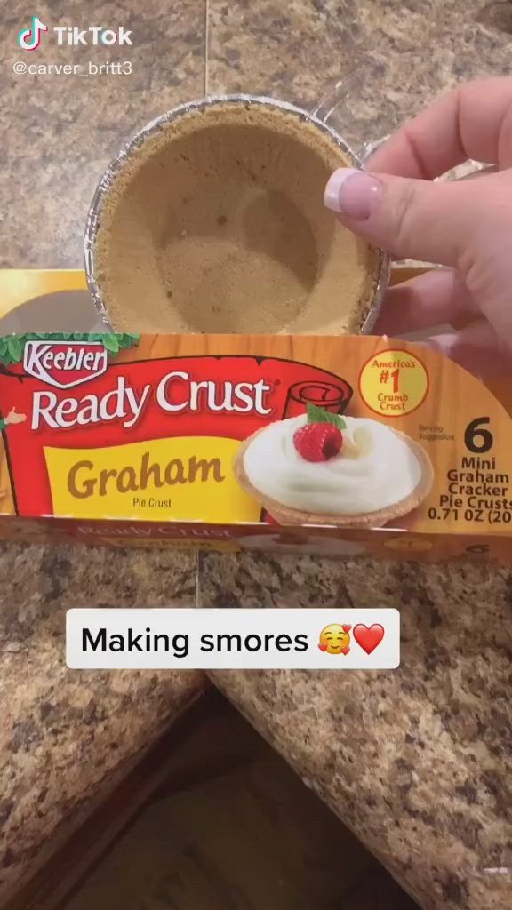 This may contain: someone holding up a box of ready crust graham crackers with a strawberry on top