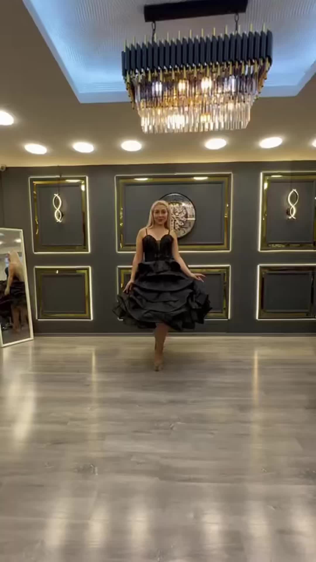 This may contain: a woman in a black dress is dancing