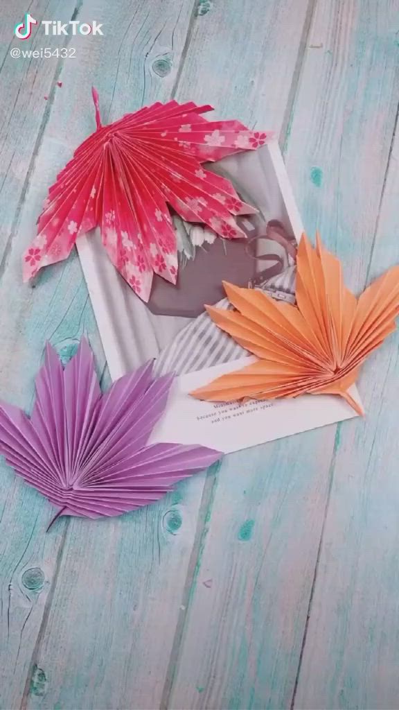 This may contain: three different colored paper flowers sitting on top of a wooden table