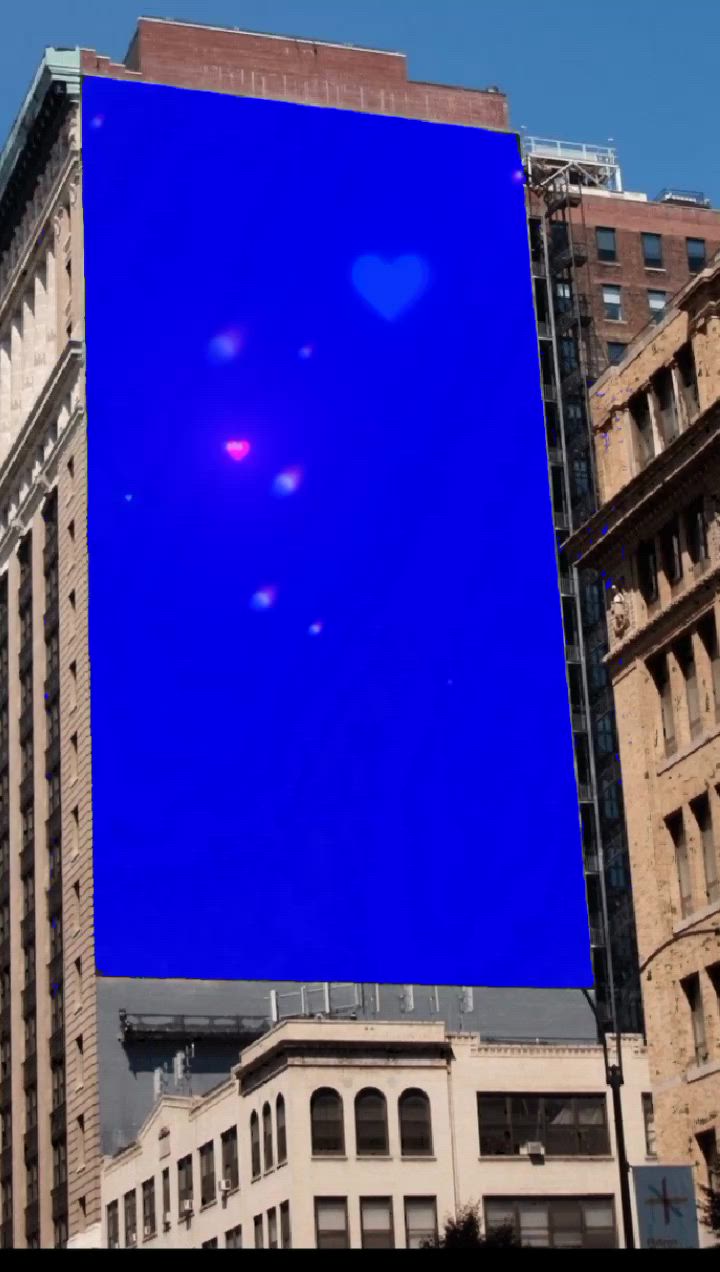 This may contain: a large blue billboard is in the middle of some tall buildings and there are no people around it