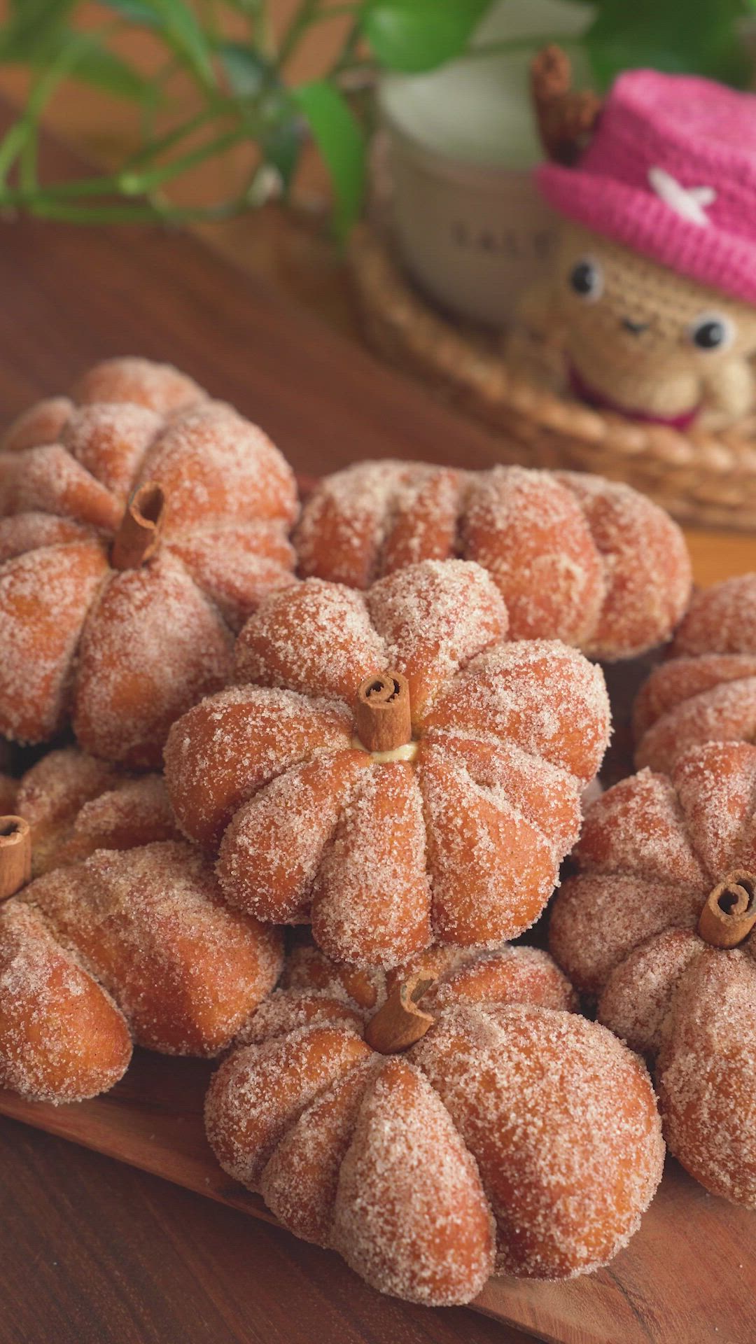 This may contain: pumpkin donuts are being held up by someone's hands on a wooden table