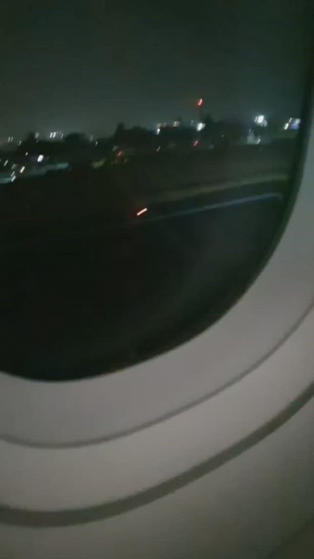 This may contain: an airplane window at night with the city lights in the distance as seen from inside