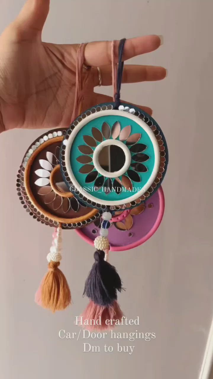 This may contain: a hand is holding a colorful keychain with tassels and beads on it