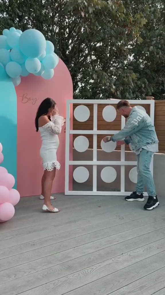 This may contain: a man and woman standing in front of a stage set up for a party with balloons