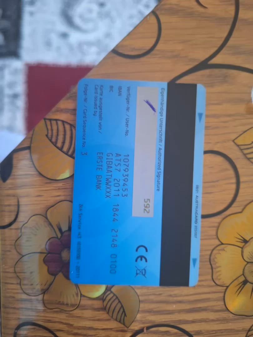 This may contain: a blue credit card sitting on top of a wooden table next to a flowered wall