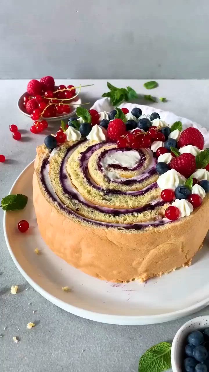 This may contain: a cake on a plate with berries and whipped cream