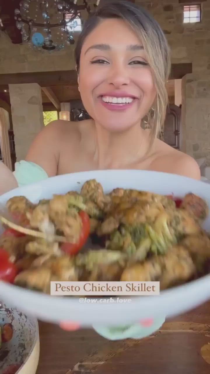 This may contain: a woman sitting at a table with a plate of food in front of her smiling