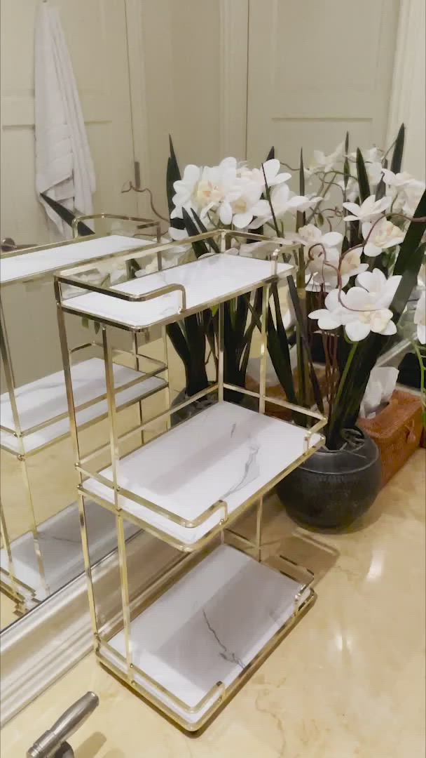 This may contain: three tiered trays with white flowers in front of a mirror on a counter