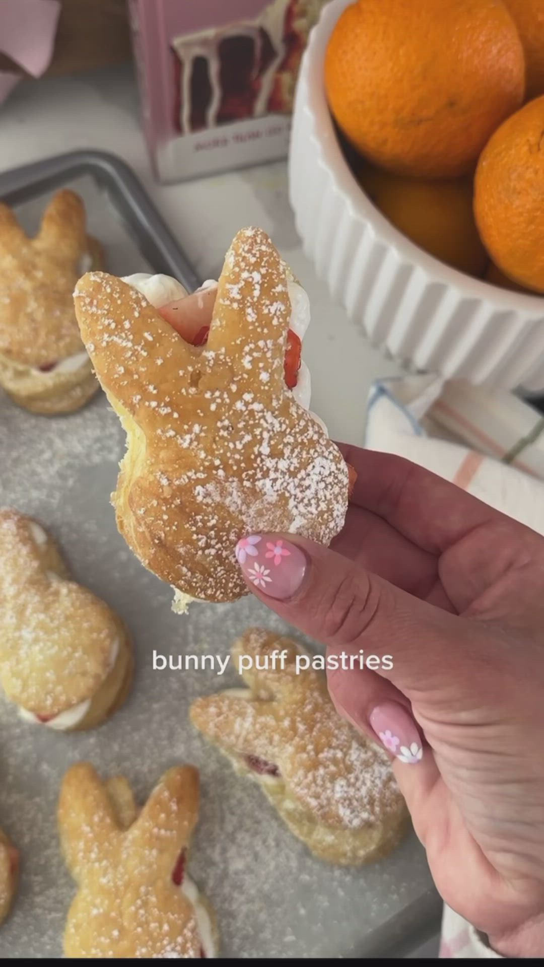 This may contain: a person is holding up a pastry in front of some oranges and other pastries