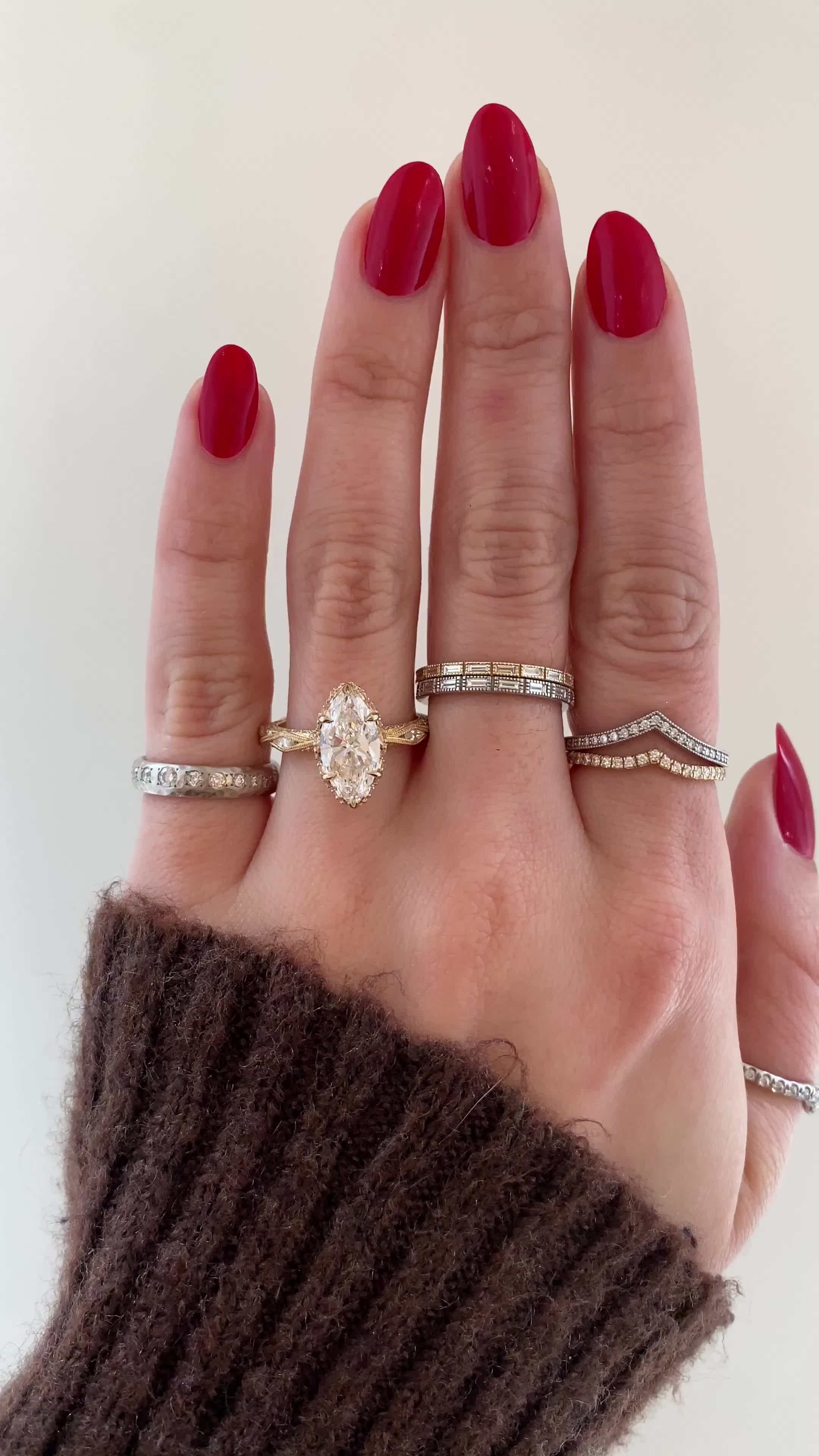 This may contain: a woman's hand with three different rings on it and one ring in the middle