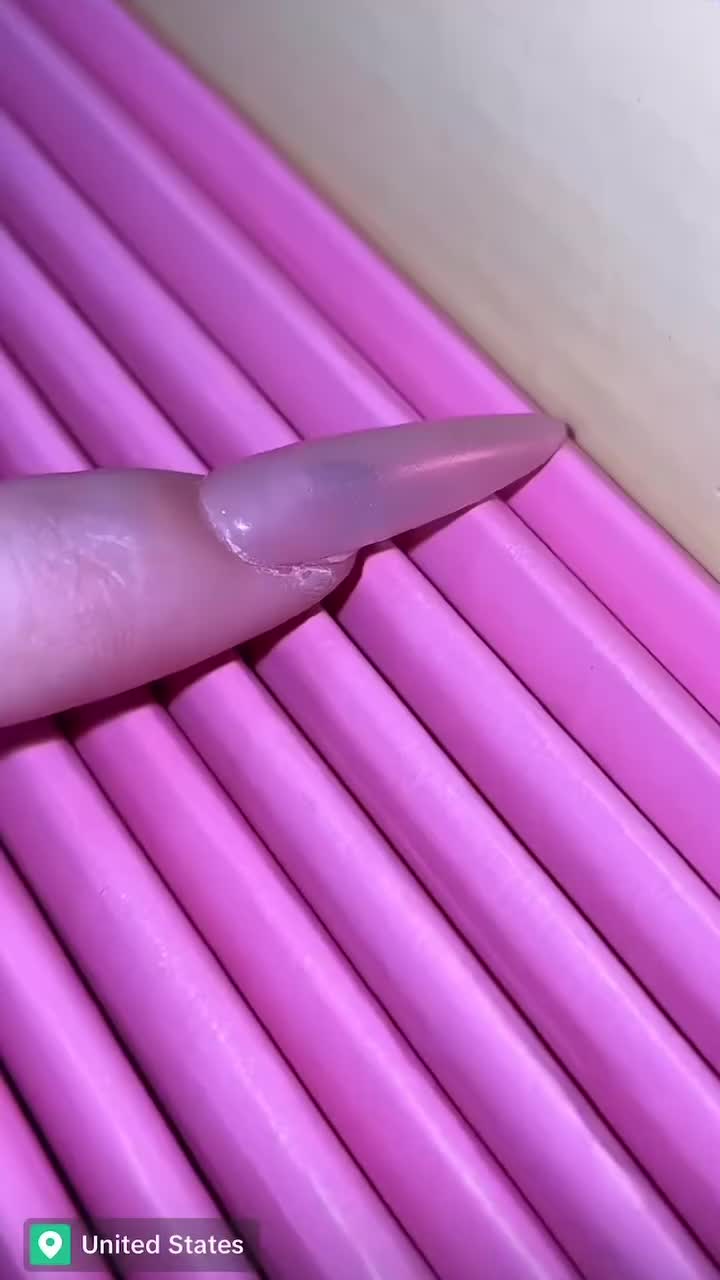 This may contain: a pink toothbrush sitting on top of a pile of purple pencils