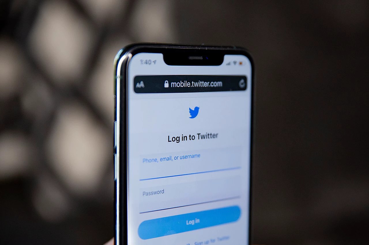 Pessoa segura telefone celular mostrando a tela inicial da rede social Twitter