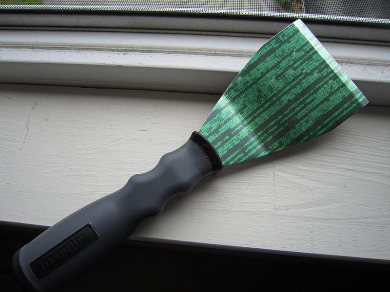 A paint scraper on a window-sill. The blade of the scraper has been overlaid with a ‘code rain’ effect as seen in the credits of the Wachowskis’ ‘Matrix’ movies.