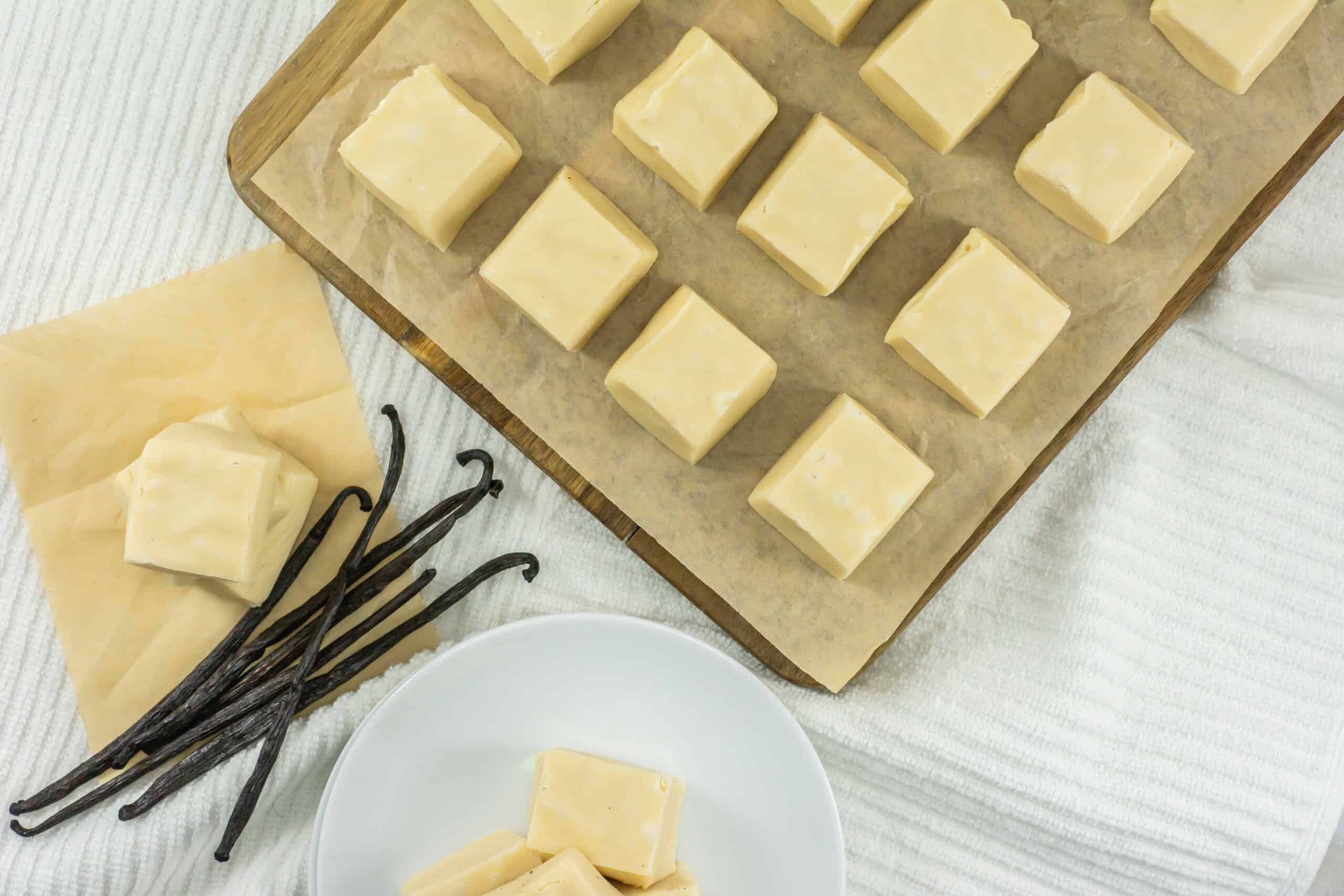 Squares of vanilla fudge on a board with vanilla bean on the side