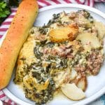 zuppa toscana casserole on a white dinner plate with a breadstick on the side