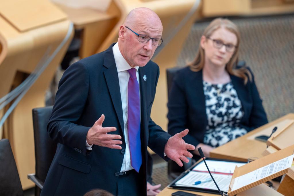 First Minister John Swinney speaks in the Scottish Parliament's chamber