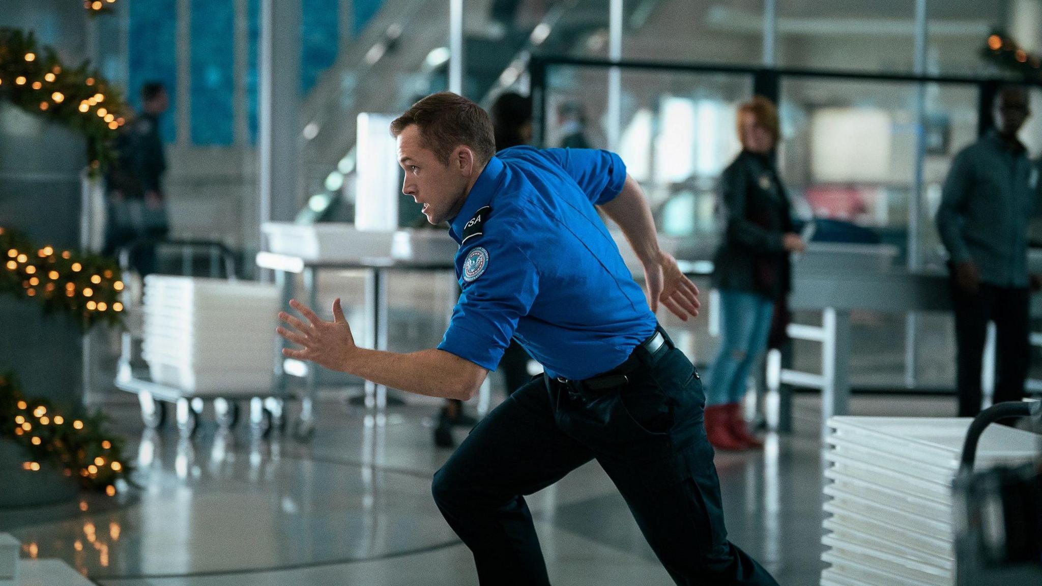 Taron Egerton as TSA agent Ethan Kopek, running through LAX.