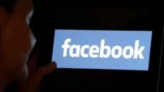 Uma mulher à sombra olha para o logotipo do Facebook em iPad