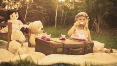 Menina tomando chá com boneca e bichos de pelúcia