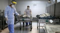 Profissionais de saúde carregam corpo em necrotério de hospital de Porto Alegre