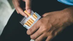 Pessoa tira cigarro de maço