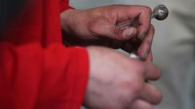 A man's hands are seen holding a crack pipe