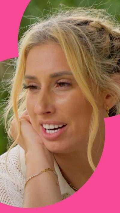 Stacey Solomon speaks. She has blonde hair, tied back and wears a white shirt