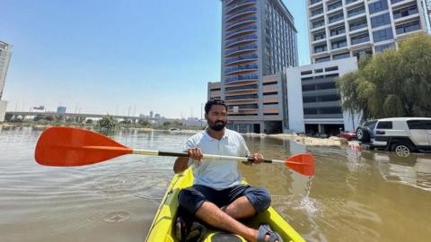 A man in a kayak in floodwater in Dubai