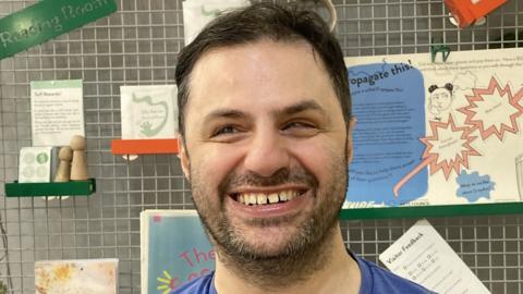 An image of Dr Yusuf Osman standing in front of a learning display.