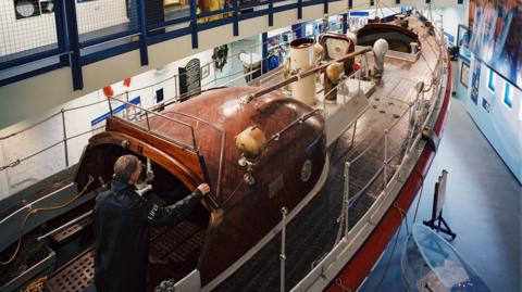 The inside of the Henry Blogg RNLI Museum, showing the old boat used by Henry Blogg with a model coxswain on board.