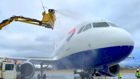 Plane being jet-washed by one of the twins, who is cleaning it from a hydraulic crane.