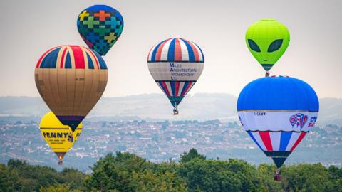 Hot air balloons float above North Somerset at the 46th Bristol International Balloon Fiesta, an annual free festival of hot air ballooning, which is the largest event of its kind in Europe, taking place over the weekend in Bristol. Picture date: Sunday August 11 2024. PA Photo. Photo credit should read: Ben Birchall/PA Wire
