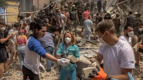 Volunteers, including medics, help emergency and rescue personnel to clear the rubble of a destroyed building at Ohmatdyt Children's Hospital 