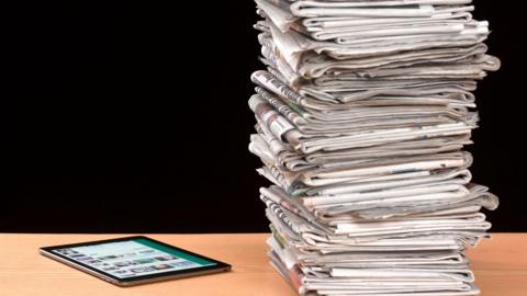 A stack of papers beside a tablet 