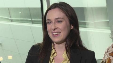 Tori Towey smiling wearing a black blazer and yellow blouse