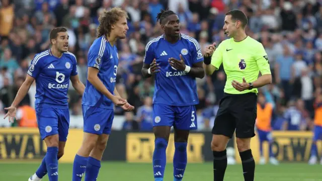 Leicester players with referee David Coote