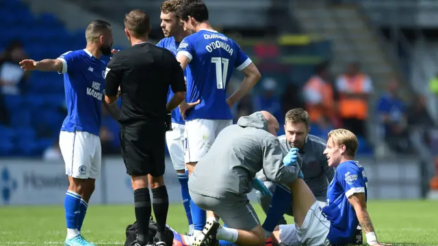 Jesper Daland of Cardiff City sits on the floor to receive physio treatment